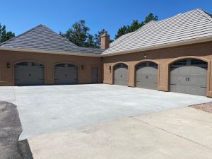 Addition of a double garage built to attach to existing three car garage in a L-shaped design, with large concrete parking pad for access to all bays. The new two-car structure was built to exactly match the existing garage doors, stucco siding and roof in color, size and shape.